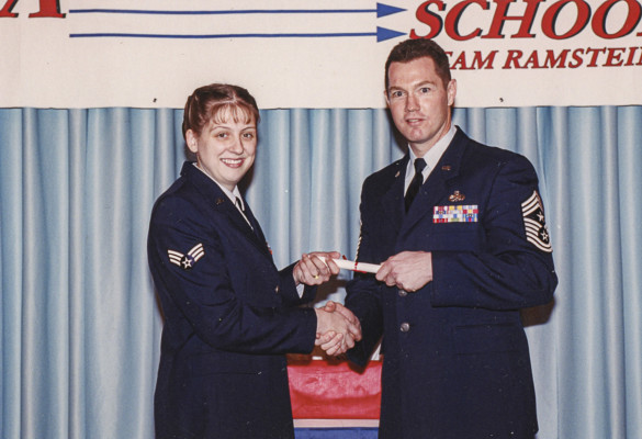 Two members of the U.S. Air Force in navy blue uniforms shaking hands.