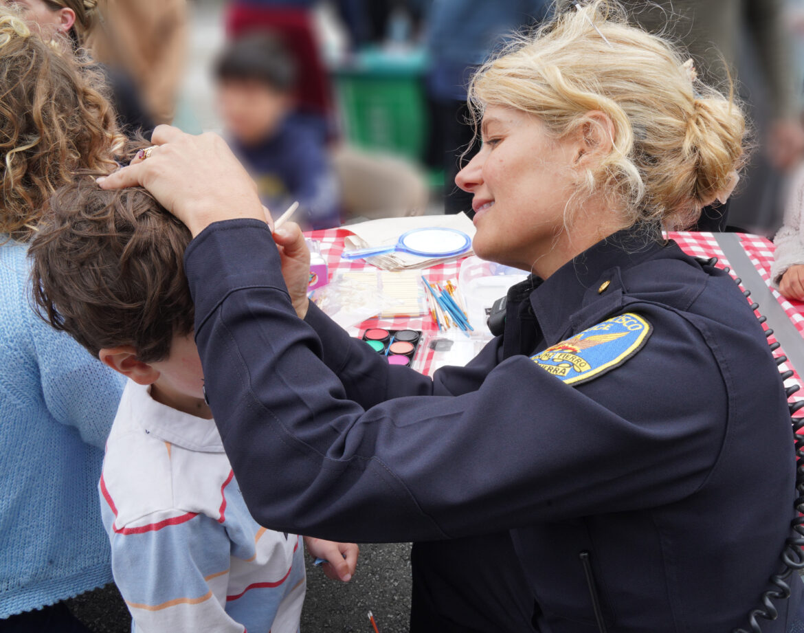SFPD Officer Jasmine Williams decorates a child's face with face paint. Photo by Bob Toy.